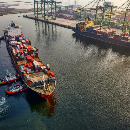 Aerial shot of cargo ships and cranes at North Jakarta port, showcasing global shipping and logistics.